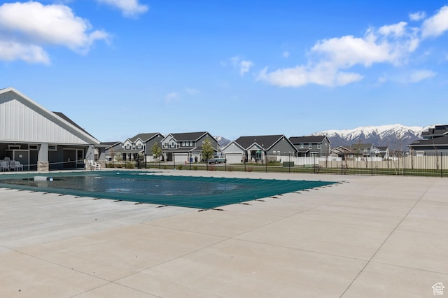 community pool with fence, a patio area, a mountain view, and a residential view