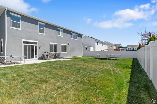 back of house with a fenced backyard, a residential view, stucco siding, and a lawn