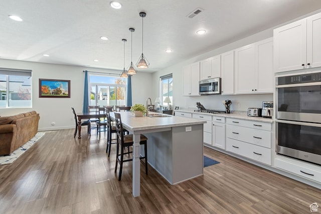 kitchen featuring dark wood-style floors, stainless steel appliances, visible vents, a sink, and open floor plan