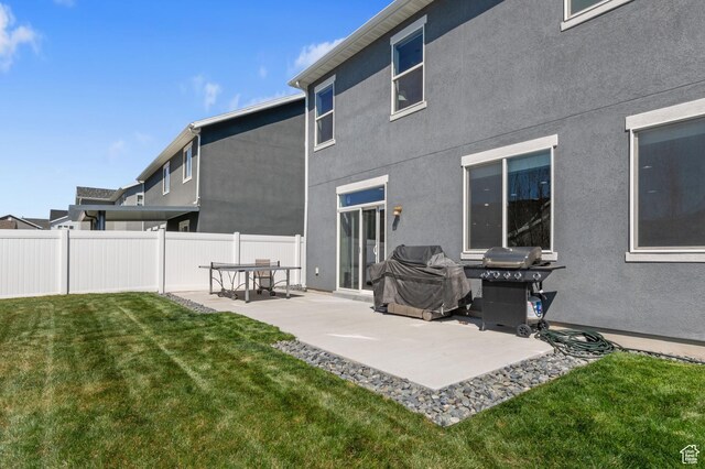 rear view of property with stucco siding, fence, a yard, and a patio
