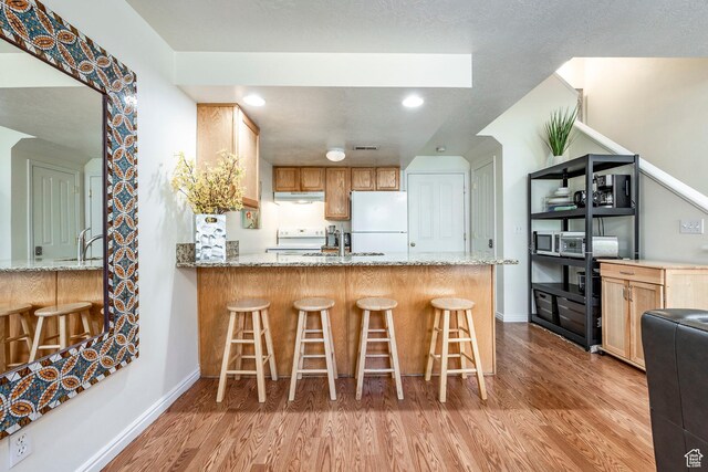 2503 S 160 E Unit 6D, Ogden, UT 84401 - kitchen featuring a peninsula, baseboards, light wood-style floors, white appliances, and light stone countertops