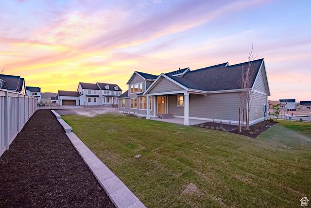 819 W Sara Dr, Saratoga Springs, UT 84045 - back of property at dusk with fence, roof with shingles, and a yard