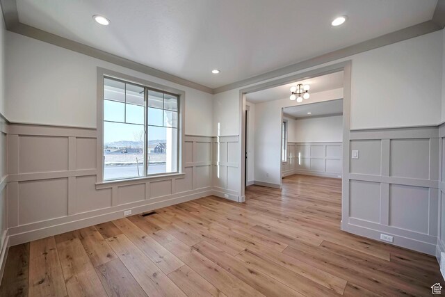 819 W Sara Dr, Saratoga Springs, UT 84045 - empty room with a decorative wall, a wainscoted wall, a chandelier, and light wood finished floors
