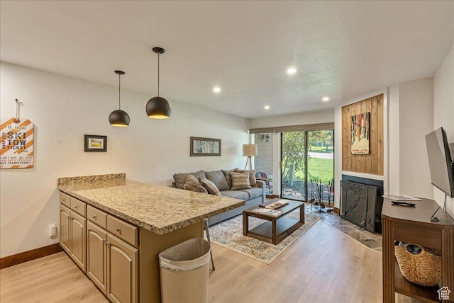 living area featuring a fireplace with flush hearth, baseboards, light wood finished floors, and recessed lighting
