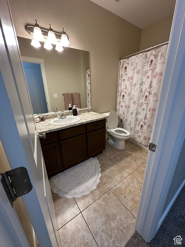 bathroom with toilet, vanity, and tile patterned floors