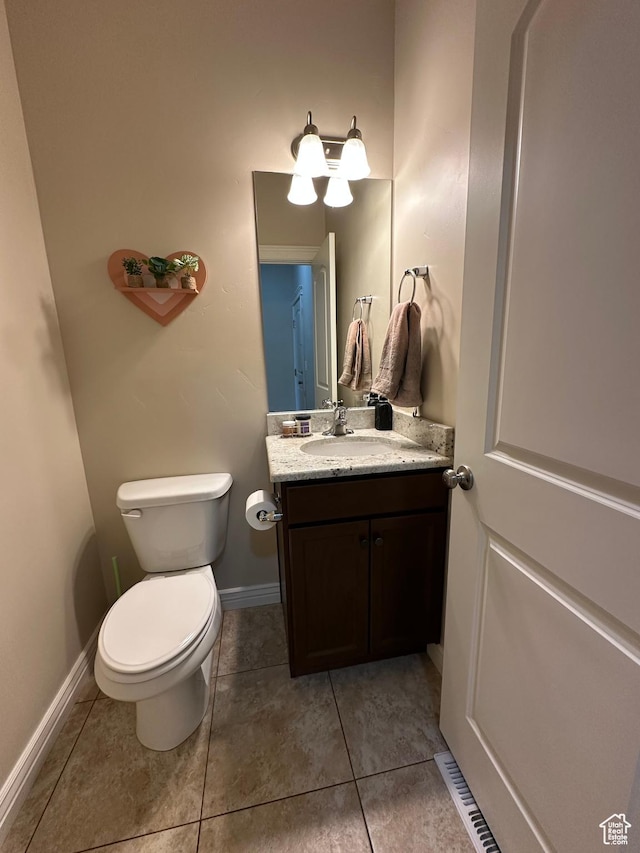 half bathroom with vanity, toilet, tile patterned flooring, and baseboards