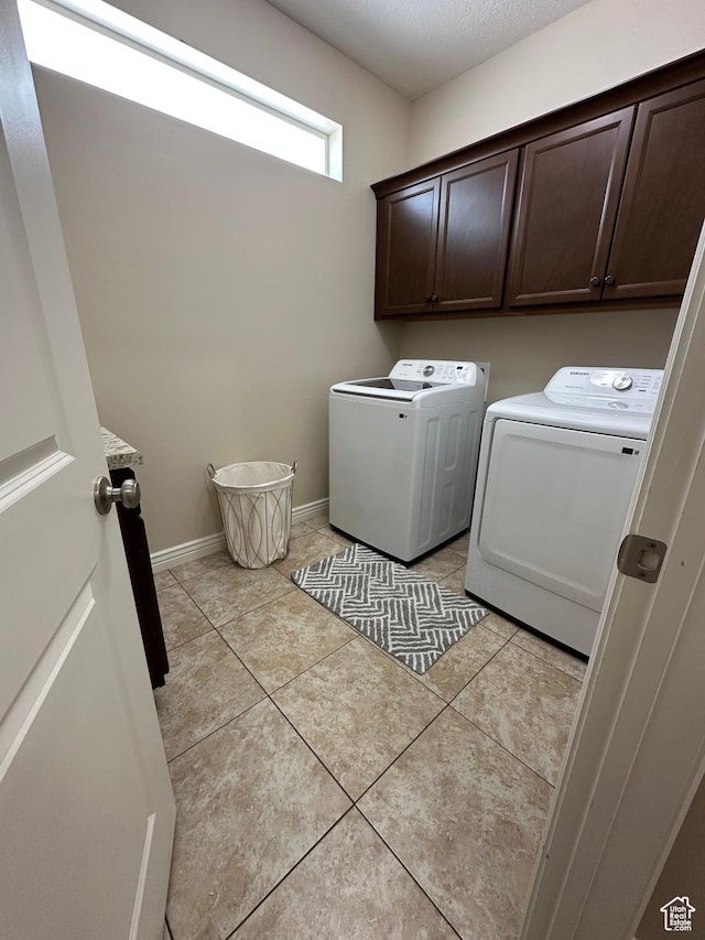 laundry area featuring cabinet space, baseboards, washer and dryer, and light tile patterned flooring