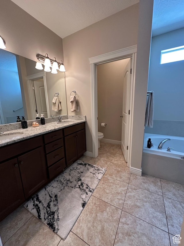full bathroom with double vanity, a garden tub, toilet, and a sink