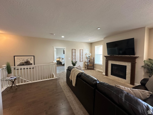 living area featuring wood finished floors, a textured ceiling, a fireplace, baseboards, and recessed lighting