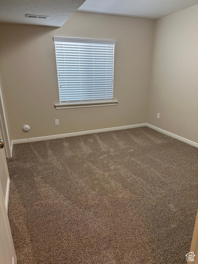 empty room featuring baseboards, visible vents, and carpet