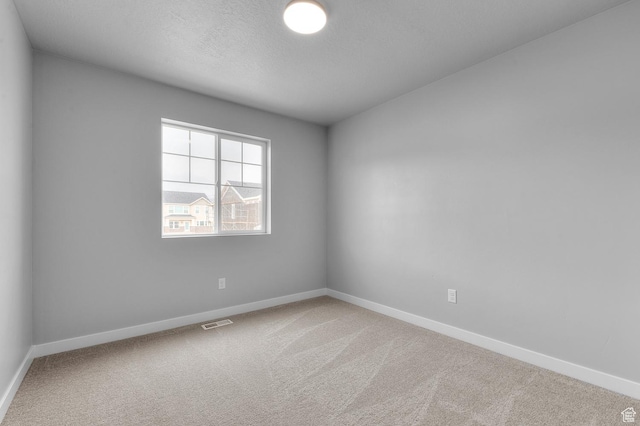 spare room featuring visible vents, carpet flooring, and baseboards