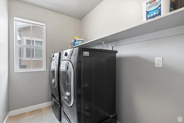 washroom featuring washing machine and clothes dryer, baseboards, and laundry area