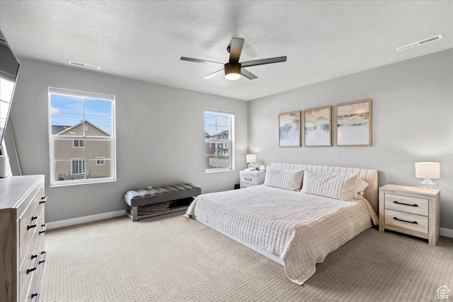 bedroom featuring a textured ceiling, carpet floors, visible vents, and baseboards