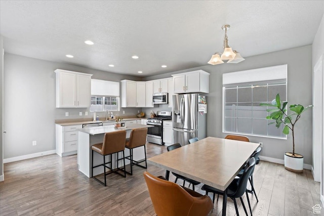 dining space featuring light wood-style flooring, baseboards, and recessed lighting