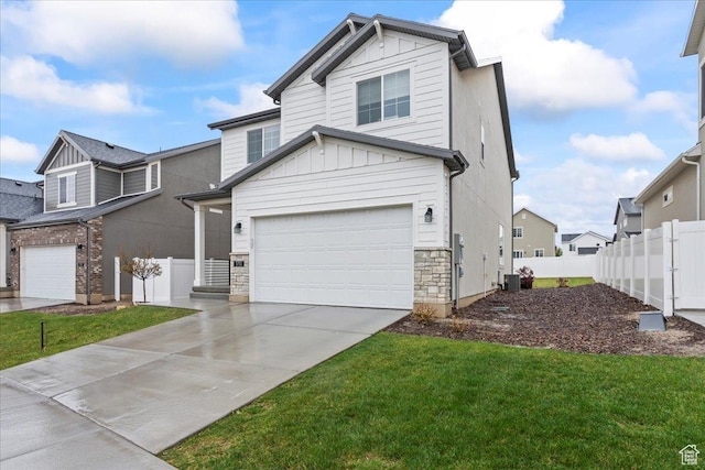view of front facade with fence, a front lawn, central AC, concrete driveway, and stone siding