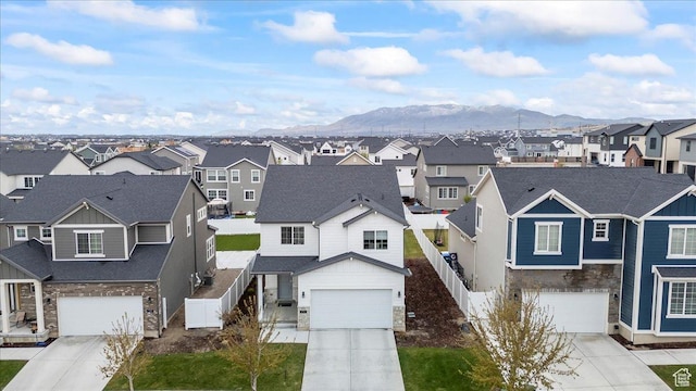view of front of property featuring driveway, fence, a residential view, and a mountain view