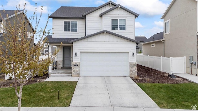 view of front of property featuring an attached garage, fence, stone siding, and a front yard