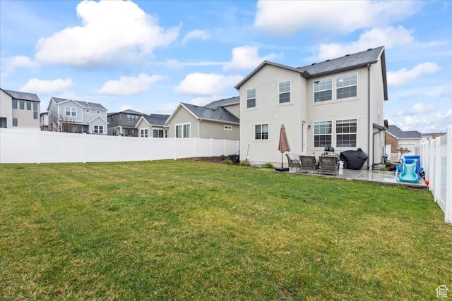 rear view of house featuring a fenced backyard, a residential view, stucco siding, a patio area, and a lawn