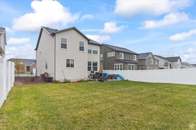 rear view of property featuring a fenced backyard, a residential view, and a lawn
