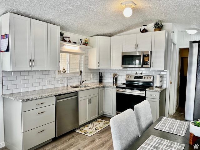 1150 W Red Hills Pkwy Unit 113, Washington, UT 84780 - kitchen with stainless steel appliances, a sink, a textured ceiling, tasteful backsplash, and light wood-style floors