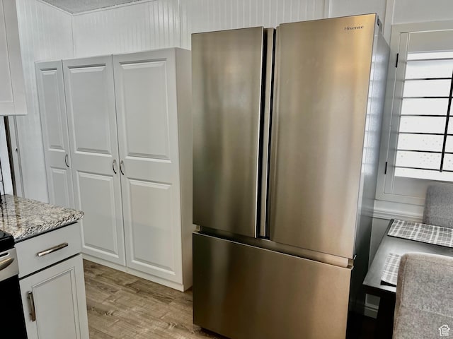 1150 W Red Hills Pkwy Unit 113, Washington, UT 84780 - kitchen with white cabinets, light wood-style flooring, freestanding refrigerator, and light stone counters