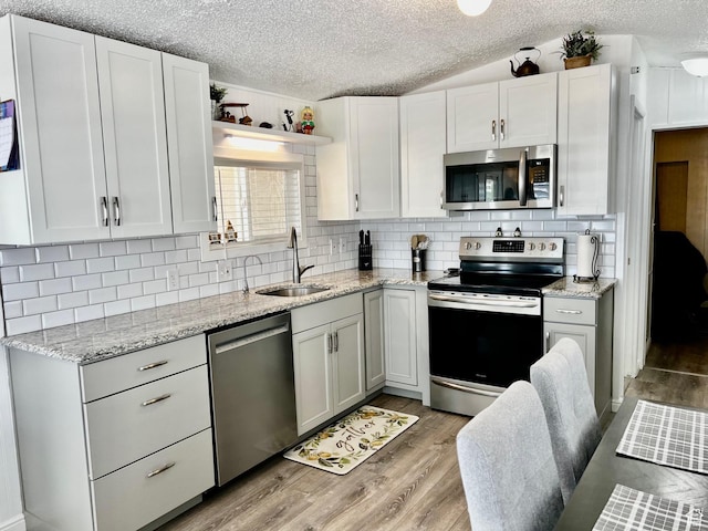 1150 W Red Hills Pkwy Unit 113, Washington, UT 84780 - kitchen featuring stainless steel appliances, a sink, light wood-type flooring, decorative backsplash, and a textured ceiling