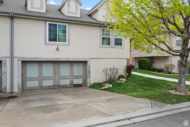 view of front of house featuring a front yard, an attached garage, concrete driveway, and stucco siding