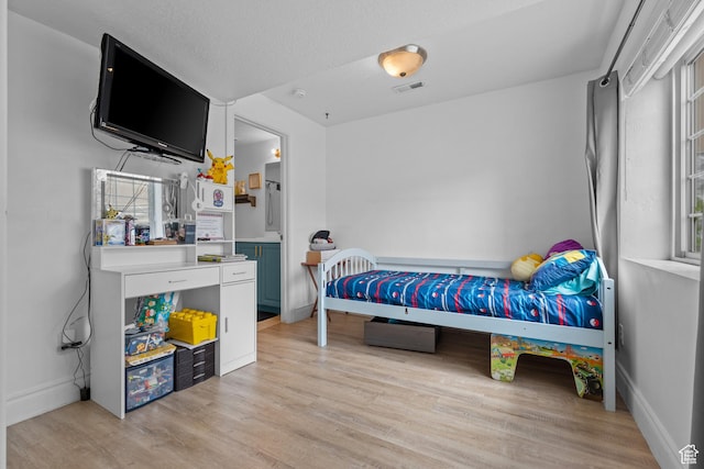 bedroom with light wood-style flooring, visible vents, and baseboards