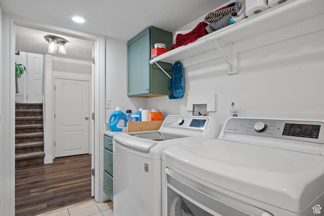 laundry room with cabinet space, a textured ceiling, washer and dryer, and light tile patterned floors