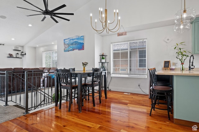 dining space with high vaulted ceiling, wood finished floors, ceiling fan with notable chandelier, baseboards, and recessed lighting