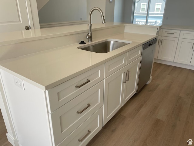 kitchen with dishwasher, white cabinets, a sink, and light wood-style flooring