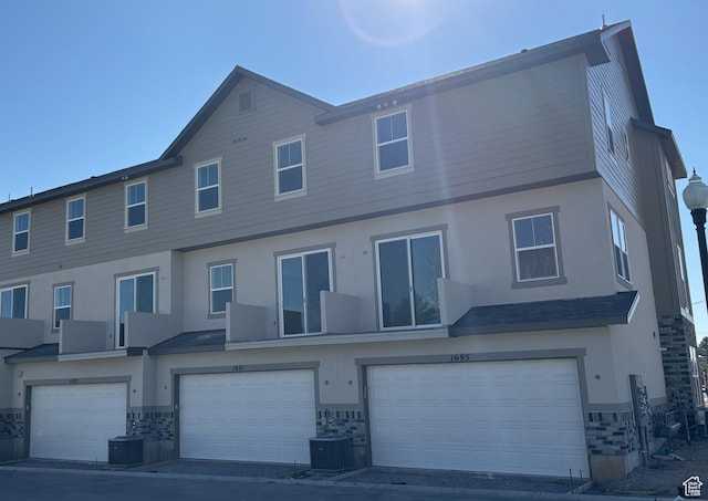exterior space with stucco siding, cooling unit, and a garage