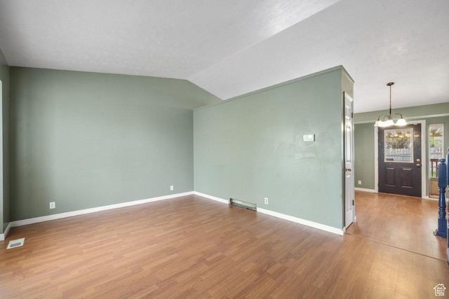 unfurnished living room featuring wood finished floors, visible vents, baseboards, and an inviting chandelier
