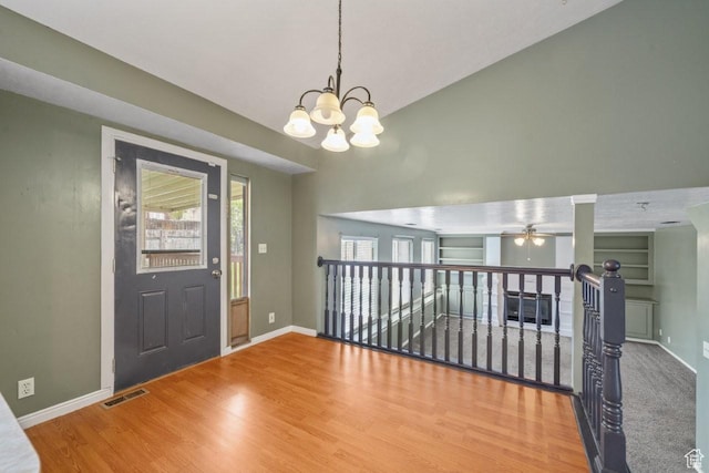 entrance foyer with wood finished floors, visible vents, baseboards, and ceiling fan with notable chandelier