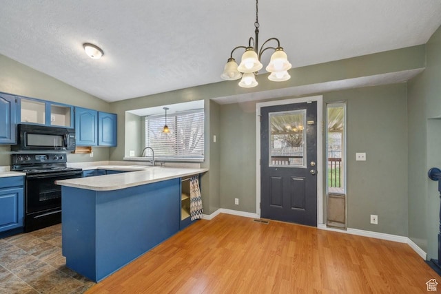 kitchen with a peninsula, a sink, blue cabinetry, light countertops, and black appliances