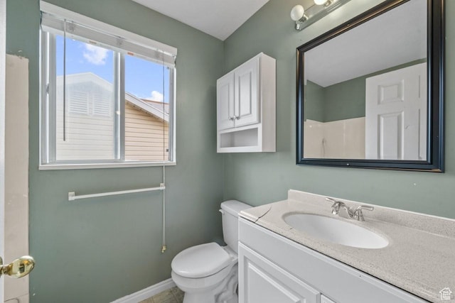 bathroom featuring toilet, vanity, and baseboards