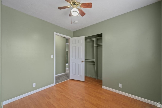 unfurnished bedroom with light wood-style flooring, a closet, a ceiling fan, and baseboards
