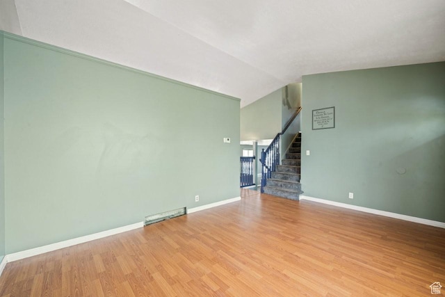 unfurnished living room featuring light wood-style floors, stairway, baseboards, and vaulted ceiling