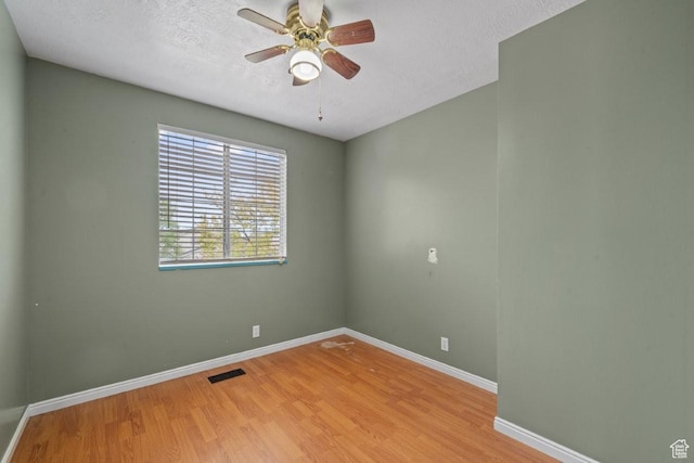 unfurnished room with a textured ceiling, wood finished floors, visible vents, and a ceiling fan