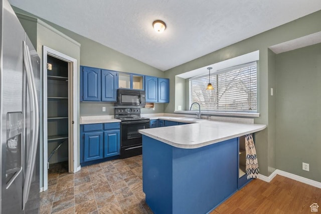 kitchen featuring light countertops, blue cabinets, a sink, black appliances, and a peninsula