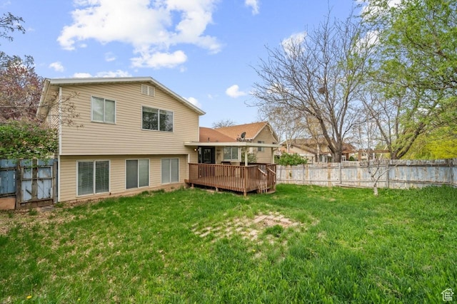 back of property with a fenced backyard, a wooden deck, and a lawn