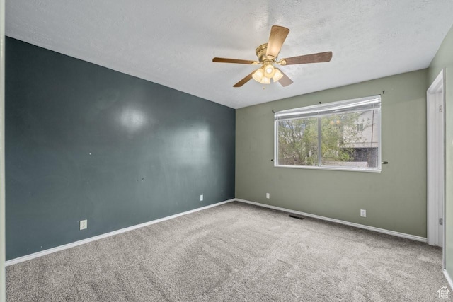 empty room featuring visible vents, a ceiling fan, carpet floors, baseboards, and a textured ceiling