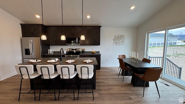 491 W 1860 N Unit 342, Tooele, UT 84074 - kitchen with appliances with stainless steel finishes, dark brown cabinets, dark countertops, and a kitchen breakfast bar