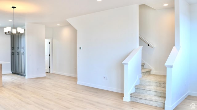 staircase with recessed lighting, wood finished floors, baseboards, and a notable chandelier