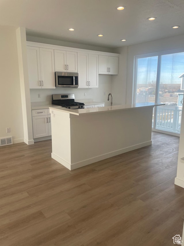 kitchen featuring light wood finished floors, stainless steel appliances, visible vents, and white cabinetry