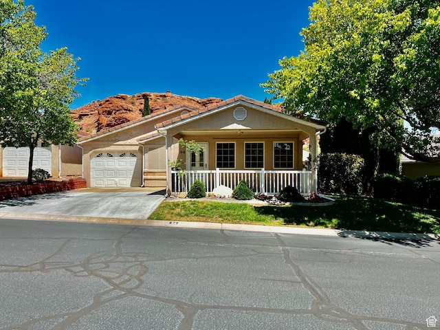 mediterranean / spanish home with stucco siding, an attached garage, driveway, and covered porch