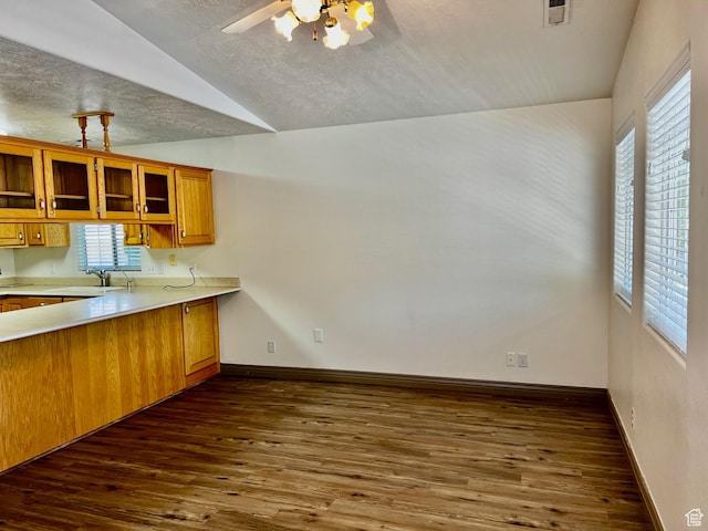 1050 W Red Hills Pkwy Unit 64, Washington, UT 84780 - kitchen featuring a textured ceiling, brown cabinetry, light countertops, lofted ceiling, and dark wood-type flooring
