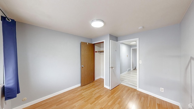 unfurnished bedroom with light wood-type flooring, a closet, and baseboards