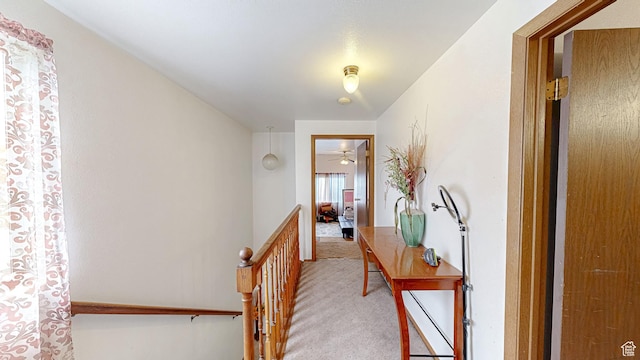 hall with light colored carpet and an upstairs landing
