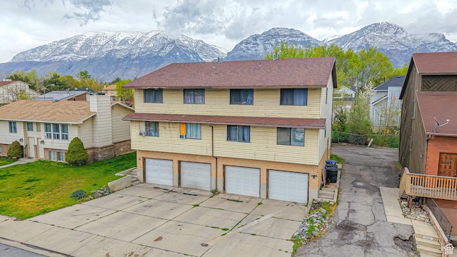 view of front of home featuring a mountain view, concrete driveway, a garage, brick siding, and a front yard